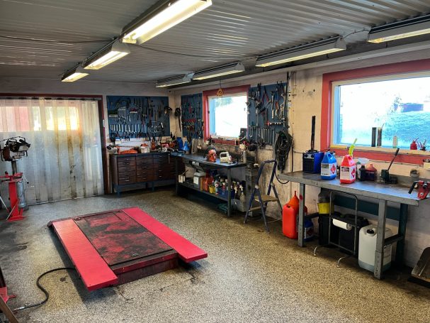 Ett garage med arbetsbänk, verktyg och en röd lyftplattform.