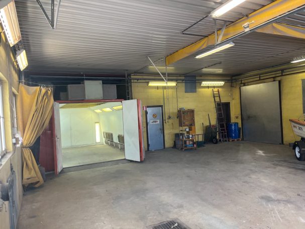 En tom garage med ljusa väggar, belysning och en öppen sektion.