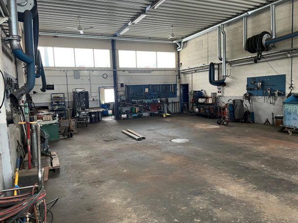 Tom verkstad med verktyg, arbetsbänkar och stora fönster för naturligt ljus.