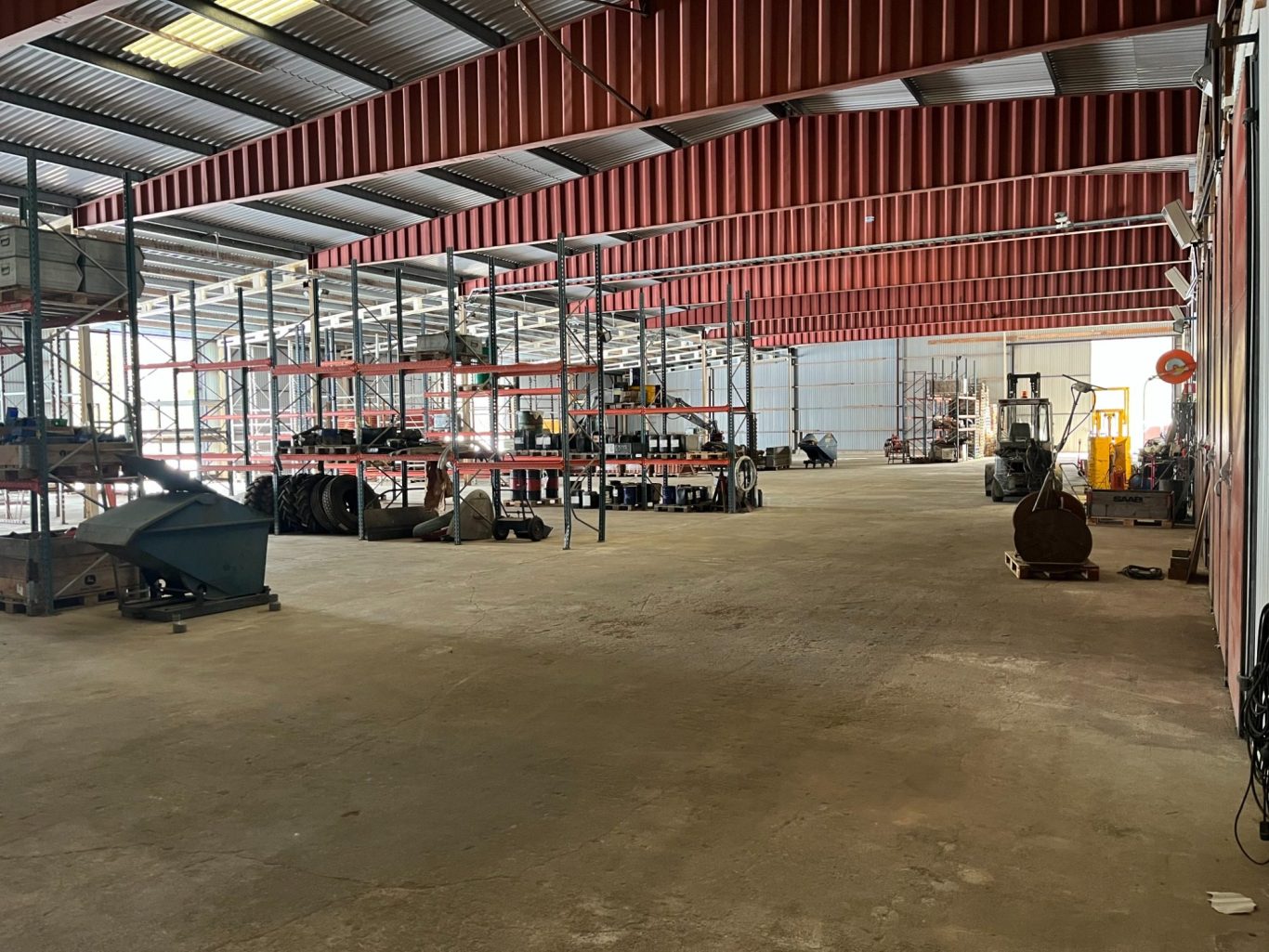 Tomt lagerutrymme med hyllor av lastpallar längs väggarna.