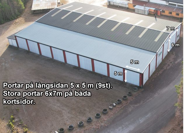 Lagerbyggnad med stora portar, belägen vid väg med grusytor runtom.