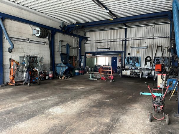 Ett garage med verktyg, maskiner och öppet utrymme för arbete.