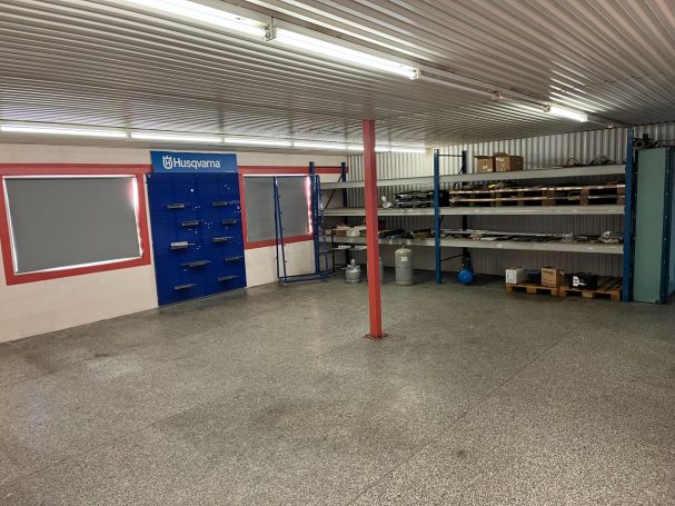 Tomt garage med hyllor, en blå dörr och grå golv.